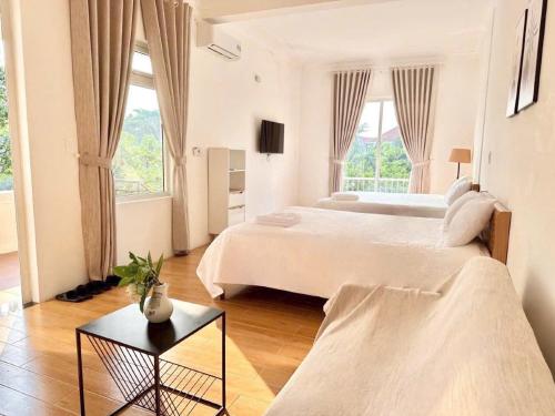 a large white bedroom with two beds and a table at Villa Rosa HueS in Thôn An Hòa
