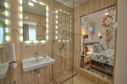 a bathroom with a sink and a mirror and a bed at Hotel Aziza in Sarajevo