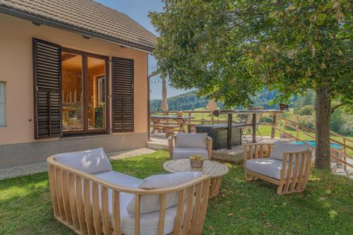 a patio with chairs and a table and a tree at Kraševec Lodge with Garden & Pool - Happy Rentals in Velike Bloke