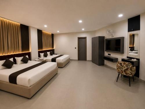 a hotel room with two beds and a flat screen tv at Hotel Golden Plaza in Amritsar
