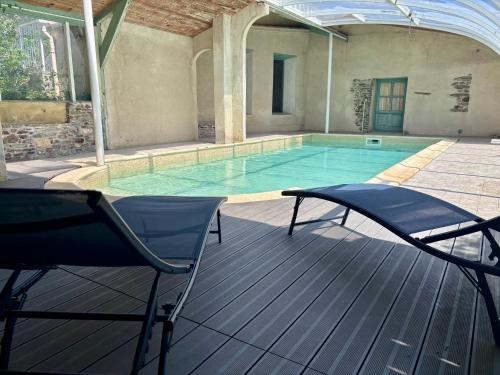 a swimming pool with two chairs in front of it at Grand Gite des Jourdets in Lairière