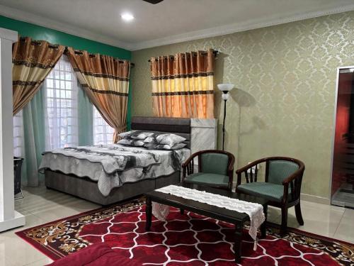 a bedroom with a bed and two chairs and a table at Farshada Homestay villa in Kapar