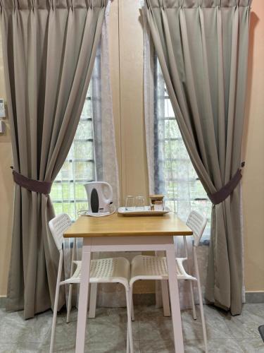 a table and chairs in front of a window with curtains at Farshada Homestay villa in Kapar