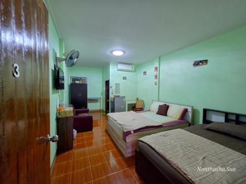a hotel room with two beds and a door at Bunrapee House in Nan