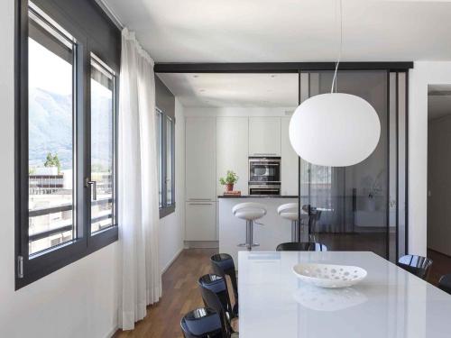 a white kitchen with a table and a large window at ibis Locarno in Locarno
