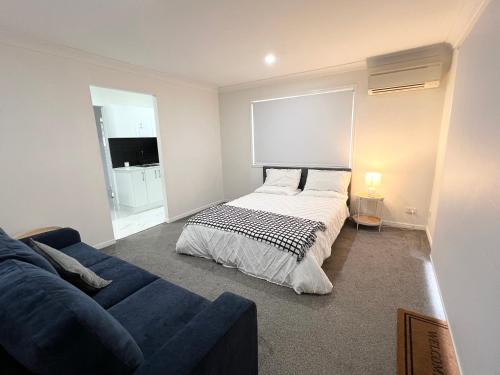 a bedroom with a bed and a blue couch at Forest view guesthouse in Runcorn