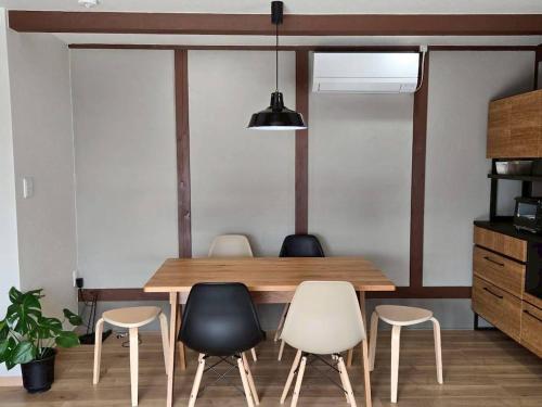 a dining room with a wooden table and four chairs at 海辺の宿なみとけ in Shodoshima