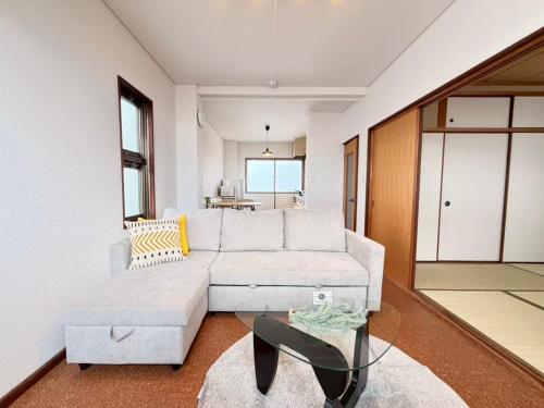ein Wohnzimmer mit Sofa und Glastisch in der Unterkunft ura tsumo in Kasaoka