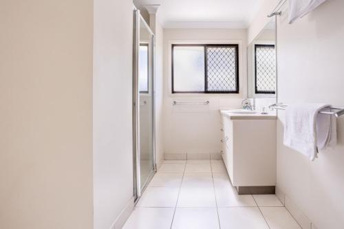 a white bathroom with a sink and a mirror at 'Flinders' in Yeppoon