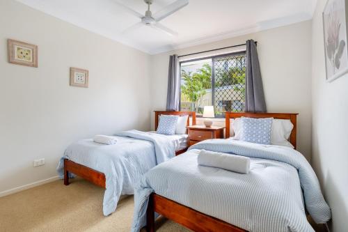 three beds in a room with a window at 'Flinders' in Yeppoon