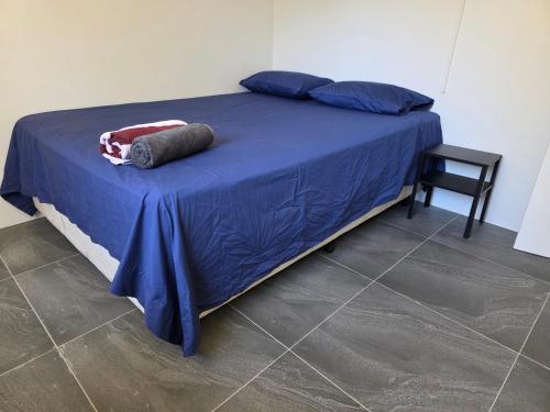a bed with a blue comforter and a chair at Room in a shared farmhouse in Kelmscott