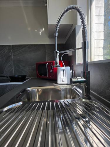 a kitchen sink with a toaster sitting on top of it at Room in a shared farmhouse in Kelmscott