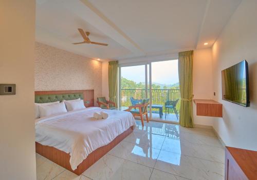 a bedroom with a large bed and a balcony at Nature Green Pool Resort Munnar by VOYE HOMES in Munnar