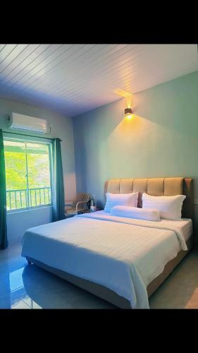 a bedroom with a large bed with white sheets and a window at Rainbow River View in Jerantut