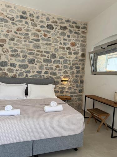 a bedroom with a bed and a stone wall at Almyra Suites in Khalíkia
