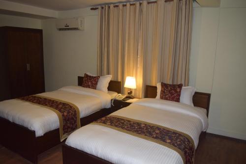 a hotel room with two beds and a window at Hotel Yambu kathmandu in Kathmandu