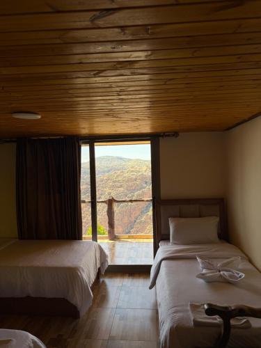 two beds in a room with a large window at Dana panorama-green camp in Dana