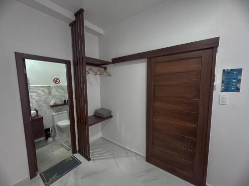 a bathroom with a wooden door and a toilet at San Cristóbal Surf House lll in Puerto Baquerizo Moreno