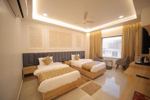 a hotel room with two beds and a television at Baba Palace in Ayodhya