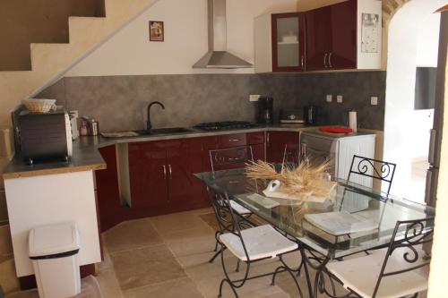 une petite cuisine avec une table et des chaises en verre dans l'établissement Gite de BEZUT, à Baron