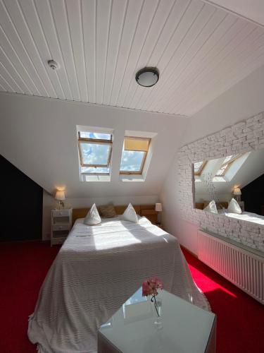 a bedroom with a large white bed and two windows at Spicīte in Ventspils