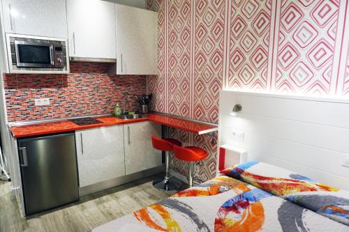 a small kitchen with a bed and a red chair at Mucho Madrid in Madrid