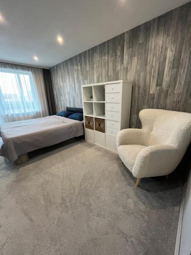 a bedroom with a bed and a chair and a dresser at Dzivoklis ar saunu in Rēzekne