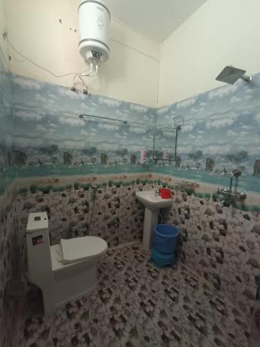 a bathroom with a stone wall with a toilet and a sink at Hotel Swagat Sarovar in Pauri
