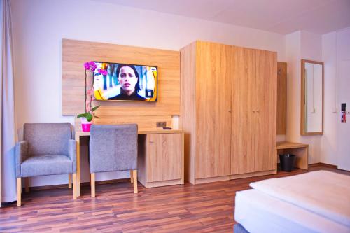 um quarto com uma secretária e uma televisão na parede em BlnCty Hotel em Berlim