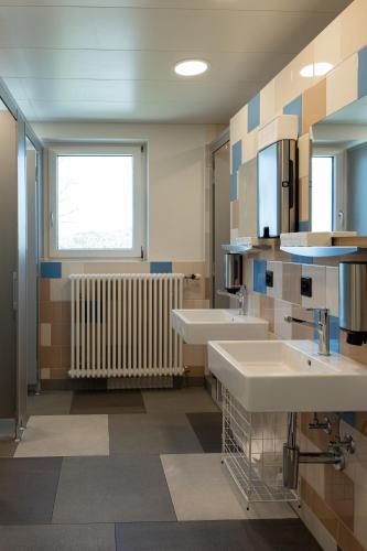 a large bathroom with two sinks and a radiator at St. Gallen Youth Hostel in St. Gallen