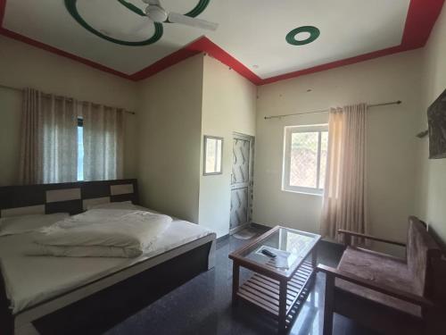 a bedroom with a bed and a table and a window at Hotel Swagat Sarovar in Pauri