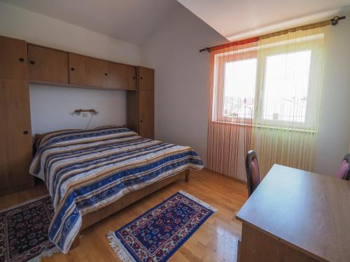 a bedroom with a bed and a table and a window at Apartman Seven Waves in Punat