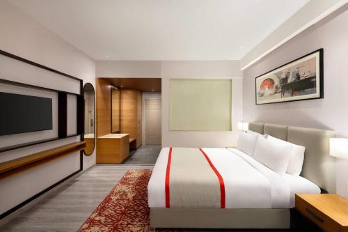 a hotel room with a bed and a flat screen tv at Ramada by Wyndham Bodh Gaya Mahabodhi in Bodh Gaya