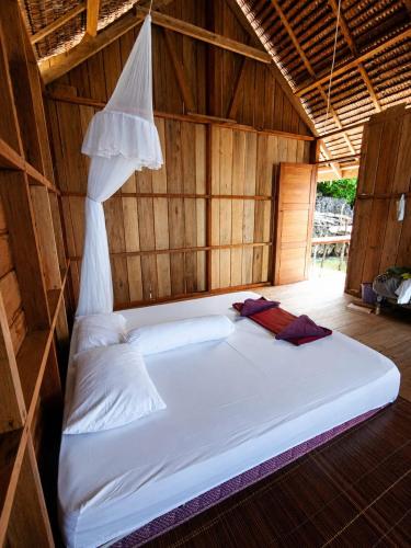 a large white bed in a room with wooden walls at Gloria Dive Homestay in Keruo