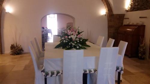 a table with white chairs and a vase of flowers at Masseria Celentano Relais & Agriturismo in San Severo