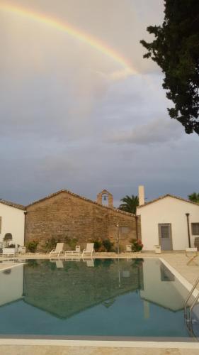 a rainbow over a swimming pool with chairs and a pool at Masseria Celentano Relais & Agriturismo in San Severo