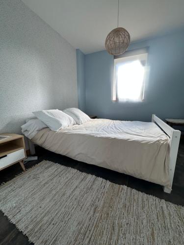 a bedroom with a white bed with a rug at Le Pressoir des Maisons de Blanche in Lengronne