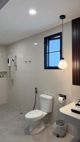 a white bathroom with a toilet and a shower at ภัสรา รีสอร์ท in Ban Nong Khla