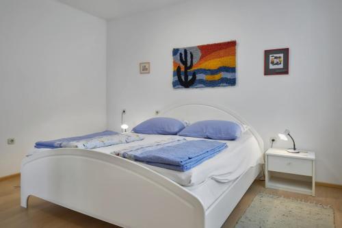 a white bed with blue pillows in a bedroom at Anka in Medulin * Istrien in Medulin