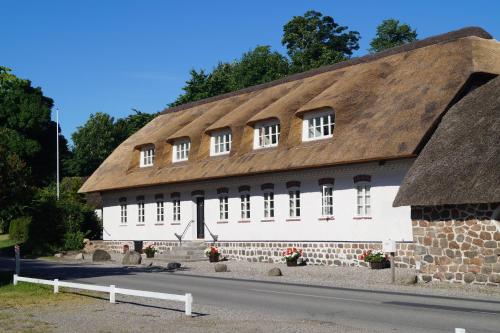 a large white building with a thatched roof at Fuglsø Kro Bed & Breakfast in Knebel