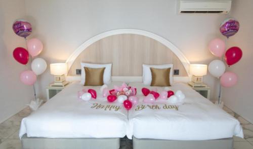 a bed with balloons and a sign that says happy birthday at at60percent in Miyako-jima