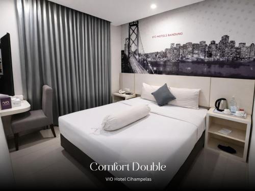 a hotel room with a bed and a desk and a monitor at Vio Cihampelas in Bandung