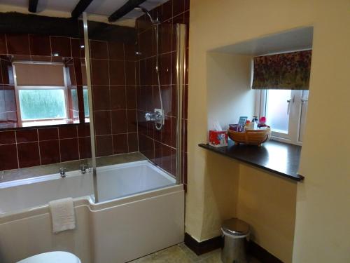 La salle de bains est pourvue d'une baignoire, d'une douche et de toilettes. dans l'établissement Burnthwaite Cottage, à Windermere