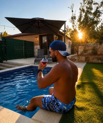 a man sitting next to a swimming pool holding a glass of wine at Casa del mir in Dayr al Qamar