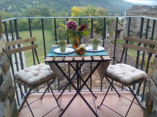Oto的住宿－Casa Villamana，阳台的桌子,配有两把椅子和一张鲜花桌