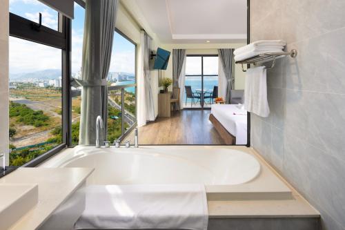 a bathroom with a tub with a view of the ocean at Xavia Hotel in Nha Trang