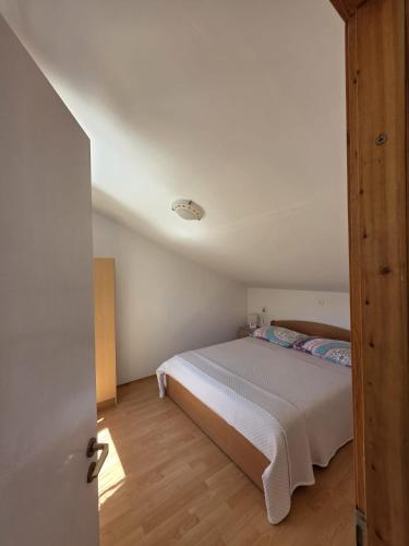 a bedroom with a bed and a wooden floor at Apartman Mihaela in Komiža