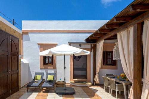 a patio with an umbrella and chairs and a table at Casa Aestas in Lachania