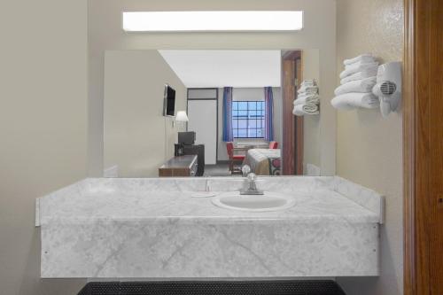 a bathroom with a sink and a living room at Super 8 by Wyndham Clarksville AR in Clarksville