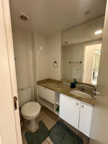 a bathroom with a toilet and a sink and a mirror at Apartamento 2 quartos 100m Prainha in Arraial do Cabo